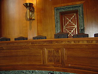Senate Banking Committee Hearing Room. There is ornate wood paneling.